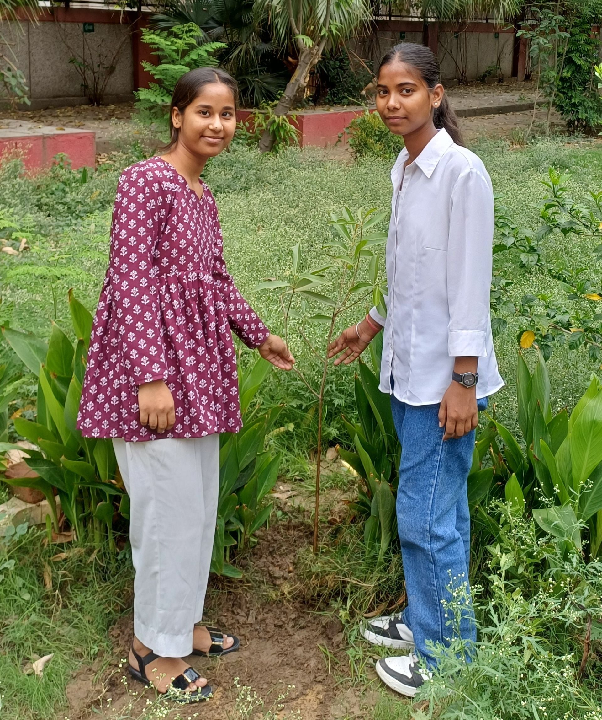 Two students point to a sapling they planted as part of a Shikshadwar tree-plantation drive